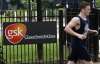 A jogger runs past a signage for pharmaceutical giant GlaxoSmithKline (GSK) in London April 22, 2014